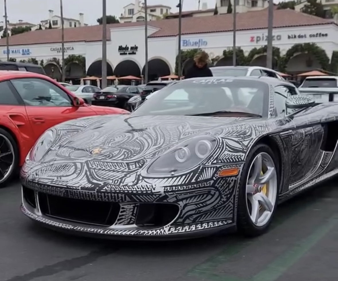 Porsche Carrera GT hand-pinstriped live at SEMA by artist Chris Dunlop, representing the intersection of Porsche design, custom car culture, and watch collecting.